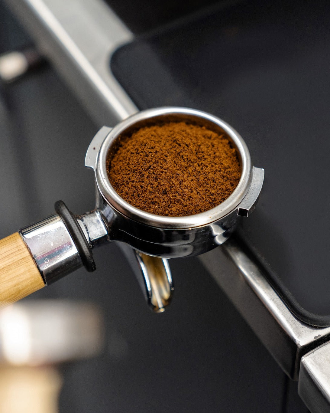 Coffee grinder with ground coffee in a clear container on a dark background